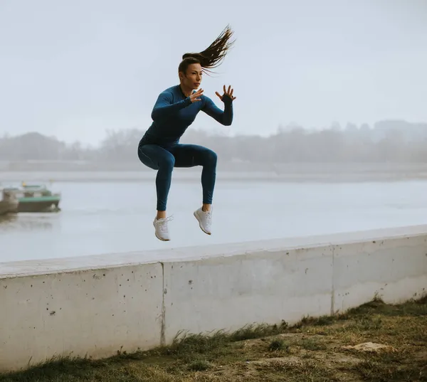 Mavi Eşofmanlı Güzel Bir Kadın Sonbahar Sabahı Nehrin Kıyısına Atlıyor — Stok fotoğraf
