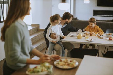 Genç anne modern mutfakta ailesine kahvaltı hazırlıyor.