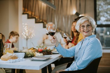 Mutlu bir aile evde kırmızı şarapla yemek yiyor.