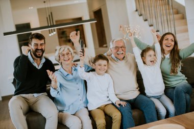Çok nesildir TV 'de futbol seyreden ve bir golü kutlayan, oturma odasındaki koltukta oturan bir aile.