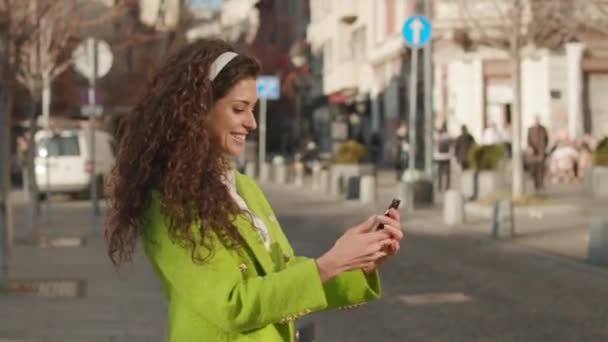 Güzel Genç Bir Kadın Sokakta Akıllı Telefonuyla Müzik Dinliyor — Stok video
