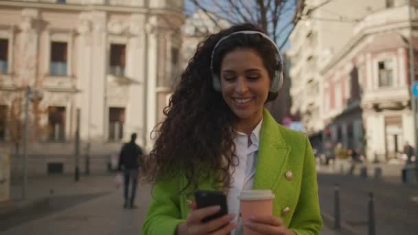 Красивая Молодая Женщина Слушает Музыку Смартфоном Улице Держит Кофе Вынос — стоковое видео
