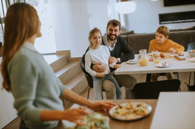 Genç anne modern mutfakta ailesine kahvaltı hazırlıyor.