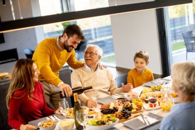 Yakışıklı genç adam evde test için babasına kırmızı şarap veriyor.