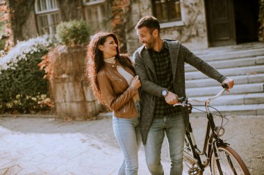 Güz parkında bisikletle yürüyen yakışıklı genç çift.