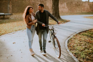 Güz parkında bisikletle yürüyen yakışıklı genç çift.