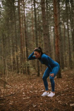 Güzel genç bayan sonbaharda orman yolunda egzersiz yaparken ara verir.