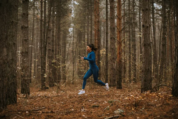 Młoda Kobieta Niebieskim Dresie Biegnie Leśnym Szlaku Jesienią — Zdjęcie stockowe