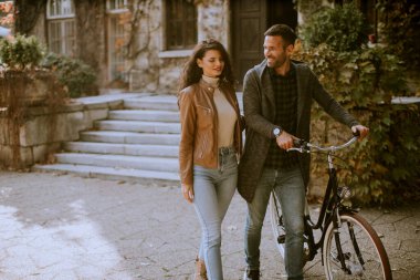 Güz parkında bisikletle yürüyen yakışıklı genç çift.