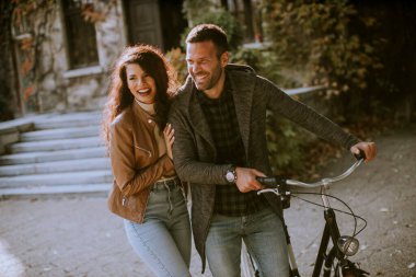 Güz parkında bisikletle yürüyen yakışıklı genç çift.