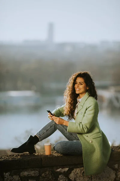 Hübsche Junge Frau Mit Lockigem Haar Benutzt Smartphone Während Sie — Stockfoto