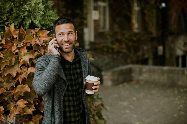 Snygg Ung Man Som Använder Mobiltelefon Och Håller Hämtkaffe Parken — Stockfoto