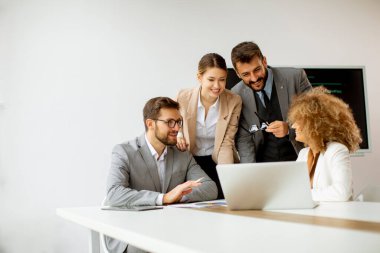 Genç iş adamları toplantı masasında oturmuş iş ve planlama stratejilerini tartışıyorlar.