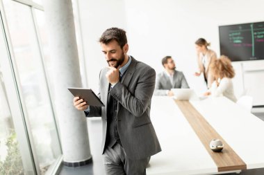 Ofiste dijital tablet kullanan yakışıklı genç iş adamı.