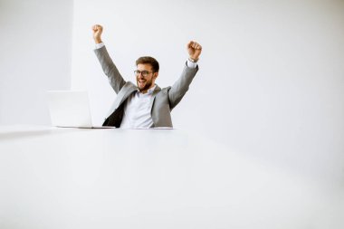 Aydınlık ofiste dizüstü bilgisayarda çalışan yakışıklı genç adam.