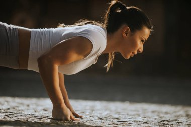 Sokakta puhsups yapan güzel bir genç kadın.