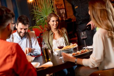 Bir grup genç restoranda yemek yiyor.