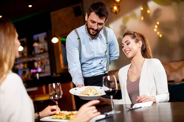 Bello Giovane Cameriere Che Serve Cibo Alle Clienti Ristorante — Foto Stock