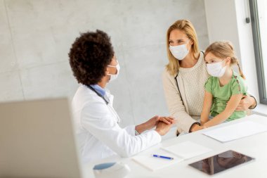 Annesi ve küçük kızı Afrikalı Amerikalı kadın doktor tarafından pediatri muayenesinde.