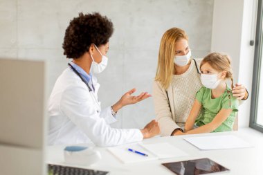 Annesi ve küçük kızı Afrikalı Amerikalı kadın doktor tarafından pediatri muayenesinde.