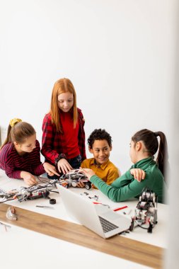 Robot sınıfında elektrikli oyuncak ve robot programlayan bir grup mutlu çocuk.