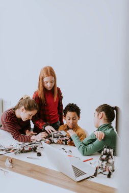 Robot sınıfında elektrikli oyuncak ve robot programlayan bir grup mutlu çocuk.
