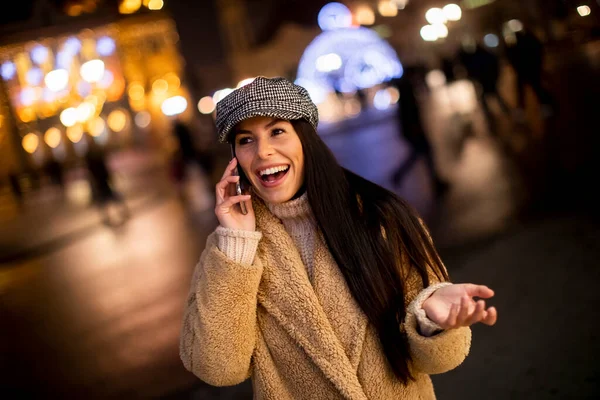 圣诞节期间 漂亮的年轻女子在街上用她的手机 — 图库照片