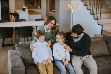 İki çocuklu mutlu bir aile. Oturma odasındaki kanepede birlikte eğleniyorlar.