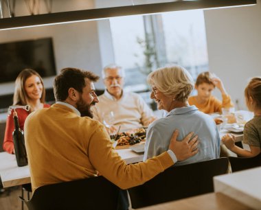 Mutlu bir aile evde kırmızı şarapla yemek yiyor.