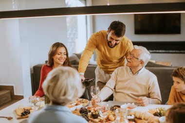 Yakışıklı genç adam evde test için babasına kırmızı şarap veriyor.