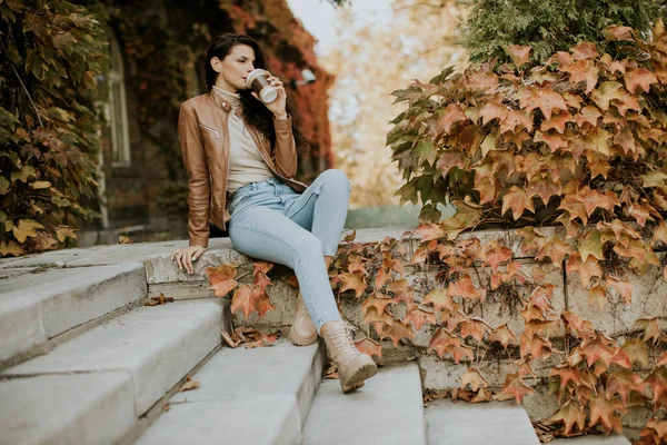 Güz gününde cep telefonu olan güzel bir genç kadın.