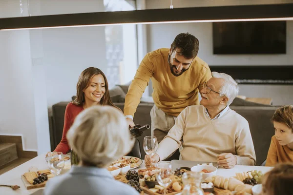 Yakışıklı genç adam evde test için babasına kırmızı şarap veriyor.