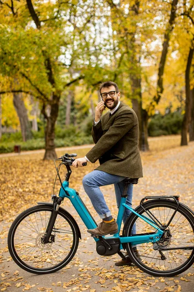 Przystojny Młodzieniec Korzystający Telefonu Komórkowego Rowerze Elektrycznym Jesiennym Parku — Zdjęcie stockowe