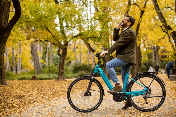 Joven Guapo Usando Teléfono Móvil Bicicleta Eléctrica Parque Otoño — Foto de Stock