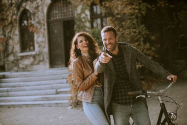 Güz parkında bisikletle yürüyen yakışıklı genç çift.
