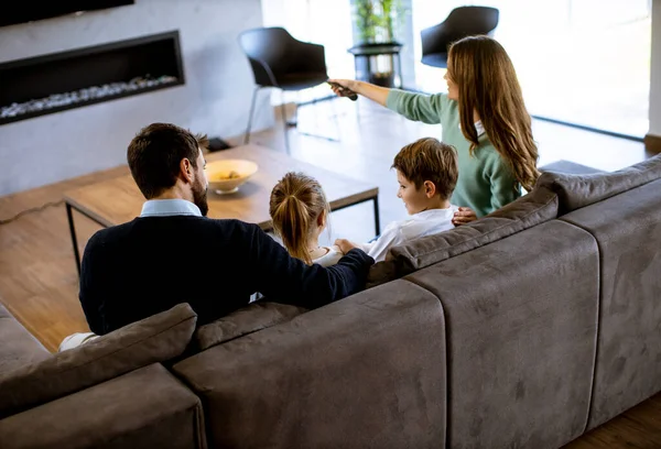 年轻的家人在客厅的沙发上一起看电视 面带微笑 — 图库照片