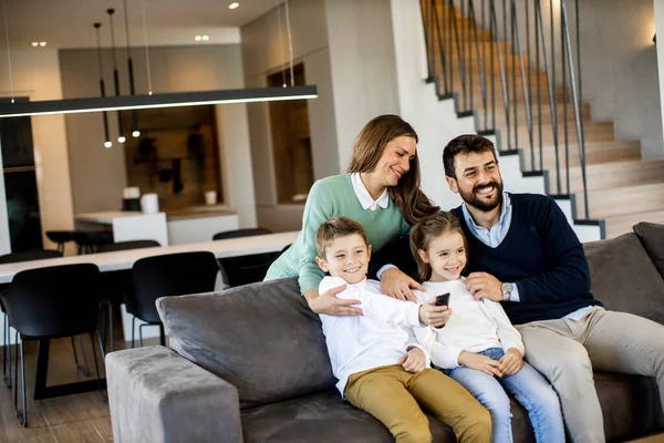 Sorridente Giovane Famiglia Guardando Insieme Sul Divano Soggiorno — Foto Stock