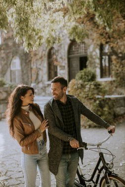 Güz parkında bisikletle yürüyen yakışıklı genç çift.