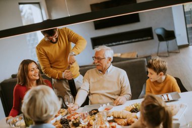 Yakışıklı genç adam evde test için babasına kırmızı şarap veriyor.