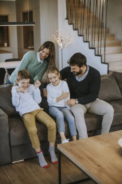 İki çocuklu mutlu bir aile. Oturma odasındaki kanepede birlikte eğleniyorlar.