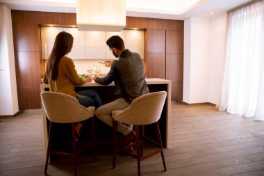 Yakışıklı genç çift mutfakta oturup beyaz şarap içiyor.