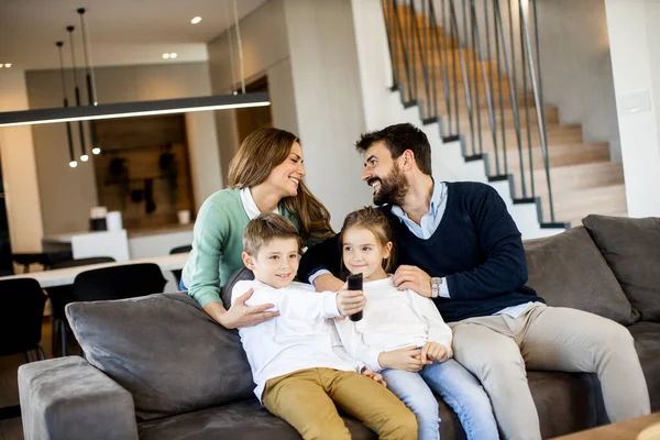 Sorridente Giovane Famiglia Guardando Insieme Sul Divano Soggiorno — Foto Stock