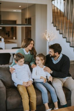 İki çocuklu mutlu bir aile. Oturma odasındaki kanepede birlikte eğleniyorlar.