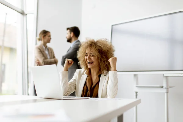 Młoda Kręcone Włosy Radosna Bizneswoman Pomocą Laptopa Biurze Młodymi Ludźmi — Zdjęcie stockowe