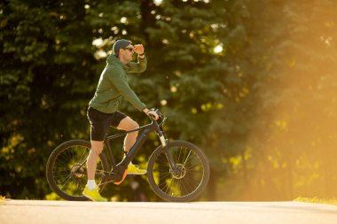 Doğada bisiklete binen yakışıklı genç adam.