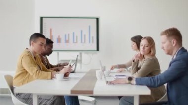 Çok ırklı genç iş adamlarından oluşan bir grup birlikte çalışıyor ve ofiste yeni bir proje hazırlıyorlar.