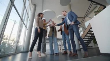 Bir grup genç pozitif iş adamı ofiste bir arada duruyorlar.