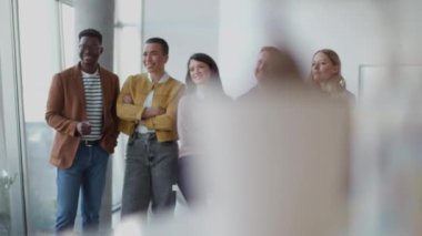 Bir grup genç pozitif iş adamı ofiste bir arada duruyorlar.