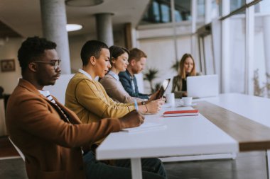Bir grup genç iş adamı birlikte çalışıyor ve ofiste yeni bir proje hazırlıyorlar.