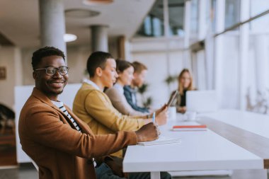 Bir grup genç iş adamı birlikte çalışıyor ve ofiste yeni bir proje hazırlıyorlar.